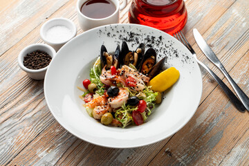Mediterranean salad with mussels, shrimps and lettuce on a wide dish on a table