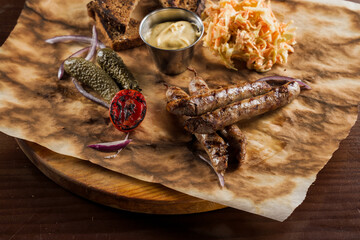 Grilled sausages with beer and vegetables with pickled cucumber, cabbage salad sauce and bread on...