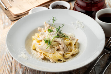 Chicken pasta with creamy sauce and grated parmesan cheese on a wide white plate