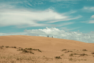 two people walking in the dunes