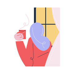 Young female standing with cup of hot drink and looking at window at home in morning