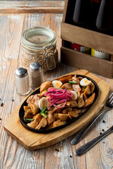 Meat and potato stew in a german restaurant in a cast-iron pan, wooden background