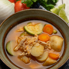 Chicken soup with rice and vegetables on white background