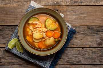 Chicken soup with rice and vegetables on wooden background