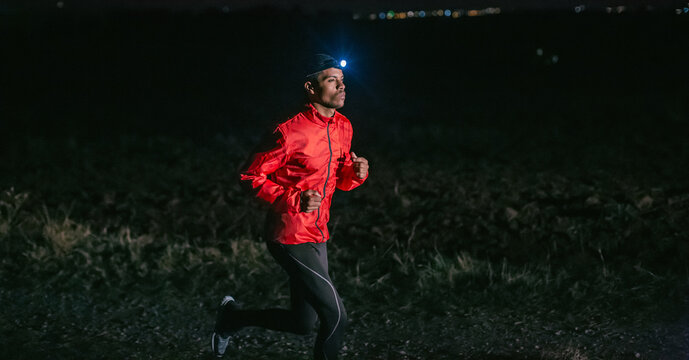 Man running on a field path at night.