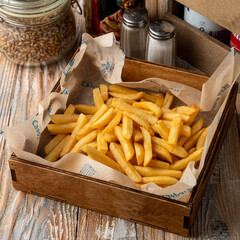 A lot of deep fried, fresh and hot french fries in a wooden tray in a pub