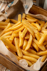 A lot of deep fried, fresh and hot french fries in a wooden tray in a pub