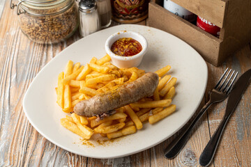 Bratwurst and fries on a pub table, top view with seasonings around