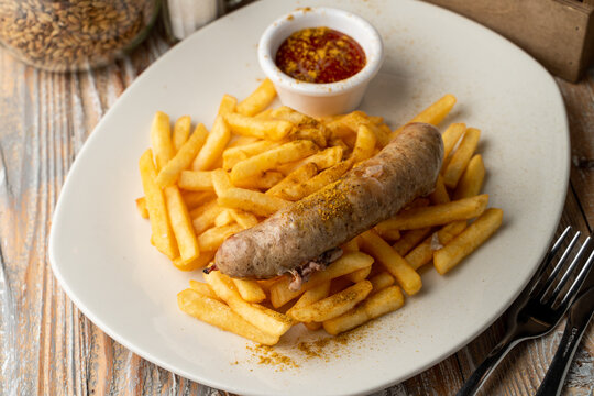 Bratwurst and fries on a pub table, top view with seasonings around