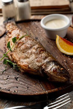 Whole grilled freshwater fish with head, food magazine photo for recipe wooden background