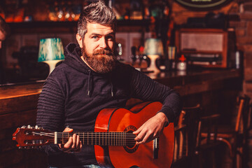 Fototapeta premium Bearded guitarist plays. Bearded man playing guitar, holding an acoustic guitar in his hands. Play the guitar. Music concept