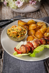 Shish kebab served with roasted potatoes and salad.