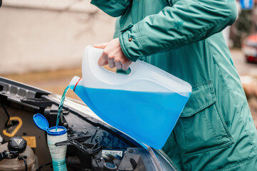 Pouring antifreeze. Filling a windshield washer tank with an antifreeze in winter cold weather.