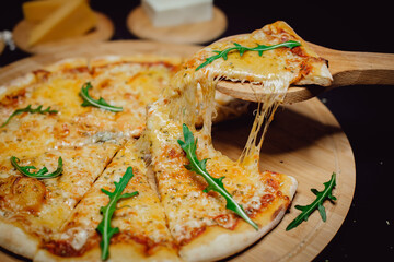 Hot pizza slice with melting cheese. Pizza with arugula leaves. A slice of pizza on a wooden spatula.