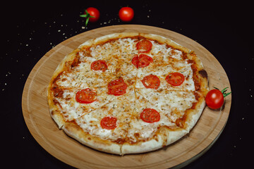 Cherry tomatoes pizza with cheese on wooden plate. Classic picture of amazing pizza.