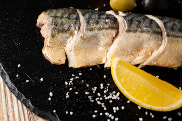 Whole trout, slowly smoked with lemon, on a black plate, top view