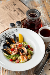 Mediterranean salad with mussels, shrimps and lettuce on a wide dish on a table