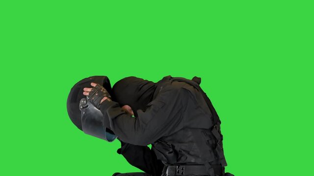 Riot policeman sitting with helmet off having rest on a Green Screen, Chroma Key.