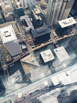 Mobile photograph of first person view of someone looking down through a glass deck up high