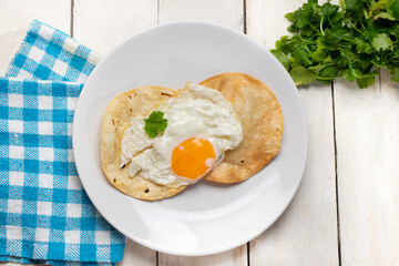 Fried egg and corn tortilla for breakfast on white background