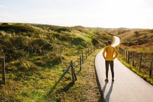 Young caucasian runner standing in the dunes during sunset.