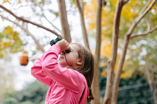 Cute young girl using binoculars outside