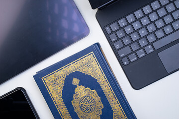 The application of technology devices and applications into digitization of Quran, or e-Quran. Online learning, or Quran recital using apps. Arabic words on the book means Holy Quran