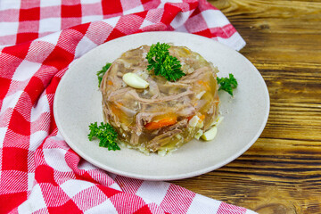 Meat aspic in a plate on a wooden table. Traditional russian dish