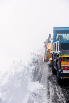 A snow plow tractor clearing the snow on the roads from a winter storm