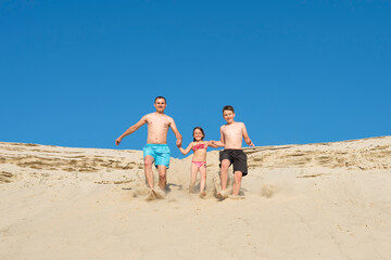 Father and children run to the beach sand on a sunny day. Seed on vacation. Recreation, sports, lifestyle