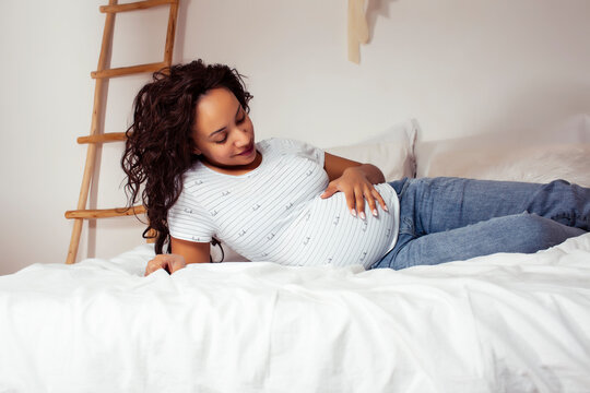 young pretty african american woman pregnant laying in bed, lifestyle people concept