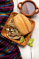 Confit pork sandwich called Torta de carnitas on white background. Mexican food