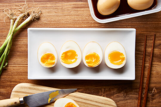 Row of boiled and marinated ramen eggs on plate.
