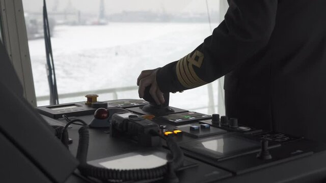 Captain on the bridge steers the ship. Hand turns azimuth controller.