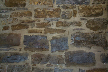 Stone wall of natural stones in different sizes; Rustic stone veneer in shades of brown and beige,