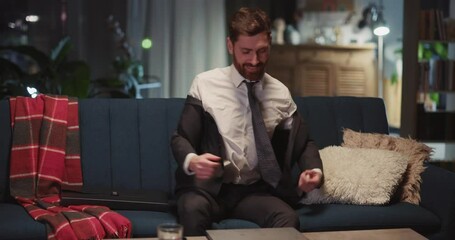 Successful young caucasian businessman arriving home after work opening laptop computer entering social media browsing internet in the apartment. - Powered by Adobe