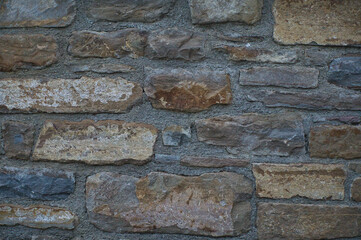 Stone wall of natural stones in different sizes; Rustic stone veneer in shades of brown and beige