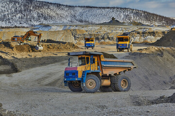 Loading and transportation of gold sands with an excavator and dump trucks. Gold mining in Kolyma