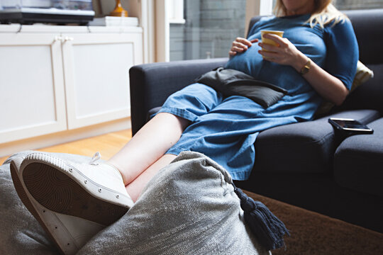 38 week pregnant women resting on couch with heat pack and herbal tea