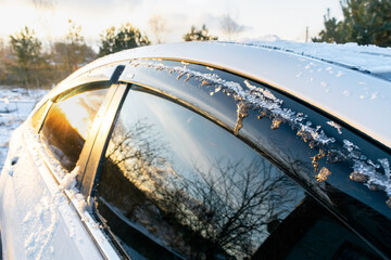Obraz premium Thin layer of fresh snow ice covering cars roof in frost in morning, evening in winter