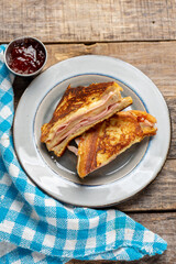 Ham and melted cheese sandwich called Monte Cristo on wooden background