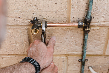 Mans hands fitting new brass cold water tap outdoors