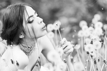 Young woman blow dandelion flower on natural background, beauty and fashion, youth and freshness.