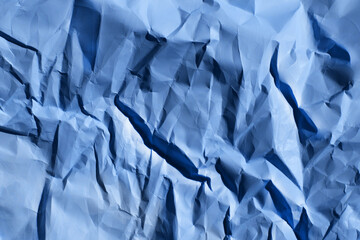 Blurry image of crumpled paper, blue colors, horizontal view.