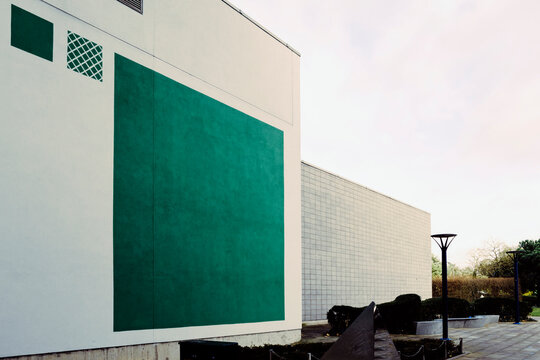 Two modern commercial buildings, one with a large green square for decoration