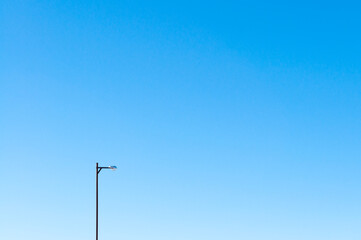A lone street lamp against the blue sky