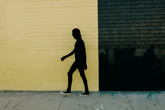 Shadow Costume walking in front of yellow wall
