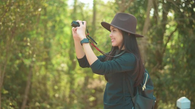 Young woman trekker taking photos of nature with camera in the woods, holidays and traveling concept.