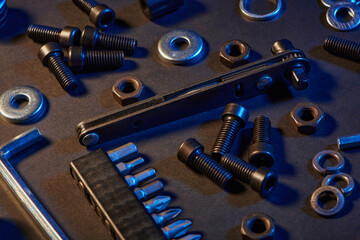 Different screws, nuts, washers, screwdrivers on black background. Hardware tools and metal bolts, nuts, and washers. Fasteners concept and goods for repair.