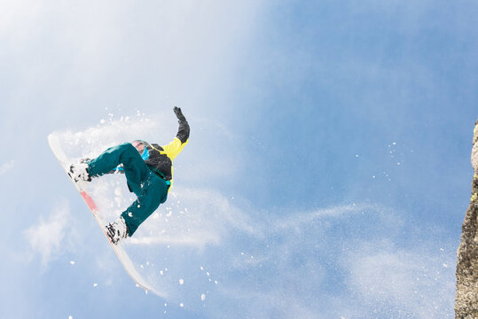 Man doing extreme midair tricks with snowboard on a sunny day